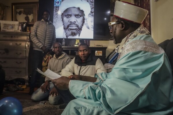 Imam Omar Niass, far right, advises migrants from Senegal, on how to apply for city services at Bronx's Masjid Ansaru-Deen mosque, Friday March 15, 2024, in New York. (AP Photo/Bebeto Matthews)